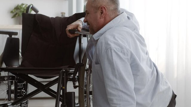 Paraplegic Man Trying To Get In Wheelchair After Falling Indoor