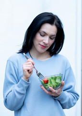 woman holding a folk and bowl with salad and eating  in summer