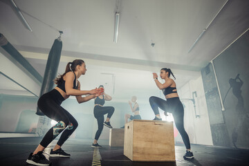 Fitness group of strong women having cross-functional training in the gym