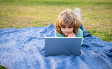 Boy kid use laptop computer learning technology relaxing on blanket natural outdoors, online courses
