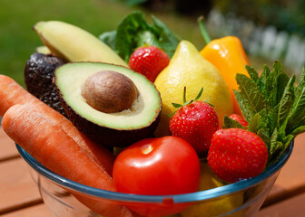 fresh fruits and vegetables in a glass bowl in the garden