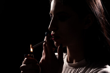 Obraz premium Silhouette of a woman lighting up a cigarette