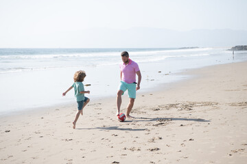 happy father and son playing football having fun on summer sandy beach family vacation, sport