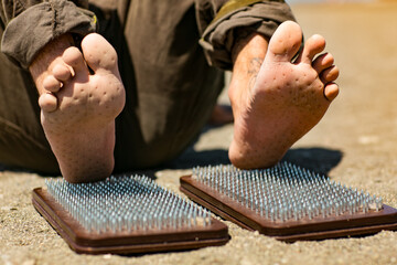 Sochi, Russia, 05.03.2021 a young stylish male yogi with tattoos stands on a sadhu board with nails