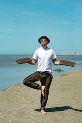 Sochi, Russia, 05.03.2021 a young stylish male yogi with tattoos stands on a sadhu board with nails