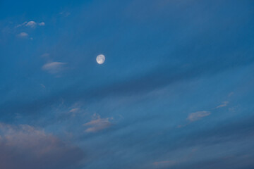 moon in the blue sky with streaking clouds