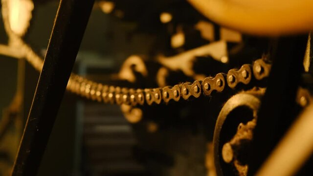close view of old abandoned machine tool in disused factory. Close up view of chain in yellow sunset light of sun. handheld footge.