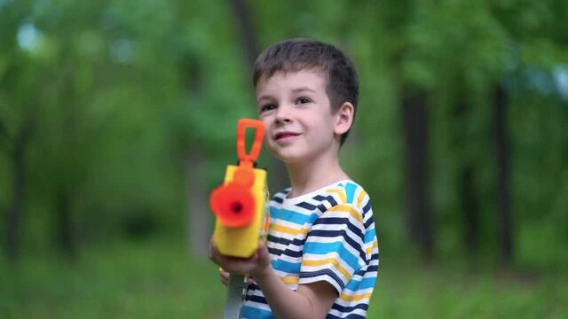 Child boy shoots from toy weapons gun outdoors