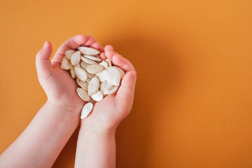 pumpkin seeds in children's palms on a brown background