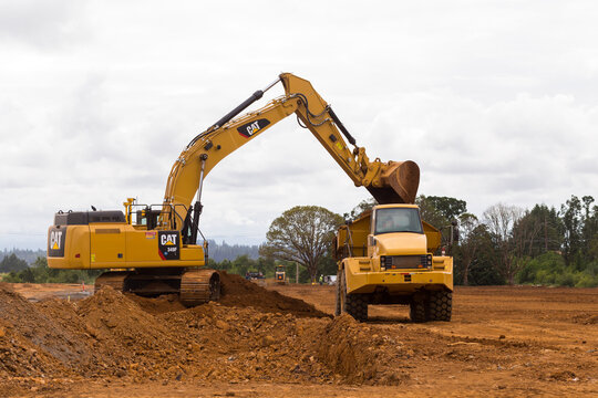 Construction Site With CAT (Caterpillar) Equipment. Excavator Loads A Truck With Soil