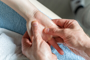 Close up on hands of unknown caucasian man therapist massaging and stretching hands of unknown woman female client