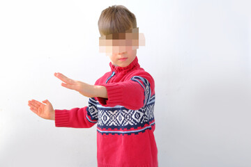 offended or punished child, a boy of 7-8 years old in a red Scandinavian sweater, kid's face is...