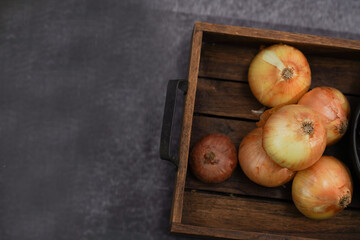 Raw onion pile in wood basket. Fresh onions with kernel on dark stone background for preparing food