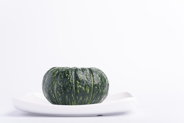 Small green pumpkin on white plate with white background, Japanese pumpkin