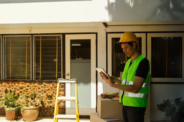 The male architect is in charge of the project, working on the renovation plan in front of the house, is writing down the repair list, renovating the house, and is preparing for work.

