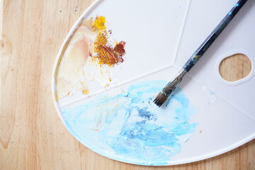 Acrylic sea and beach painting on drawing stand with palette and brush. Blue wave on golden sand hand painting with brush and knife palette technique. Art on canvas.