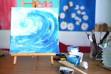 Painter paint acrylic on canvas with brush with blue on frame. Artwork as hobby or occupation for artist. Woman creates artwork by mix color and decors picture as hard copy art.