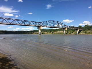 A view of a beautiful walking bridge crossing over a river from the perspective of the beach down...