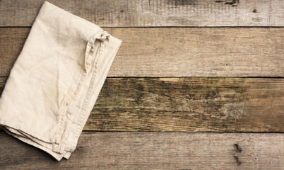 folded beige linen towel on a table made of old gray wooden boards, top view