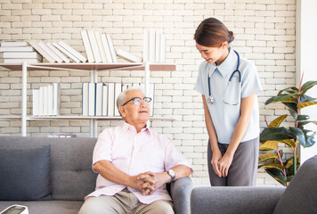 senior man at the nursing home concept. Nurse is with an elderly man sitting on armchair in living room at the care center nursing home looking together
