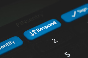 Online banking card reader keypad. Close up to the blue respond button in black background