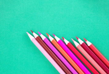 Colorful pencils on green background