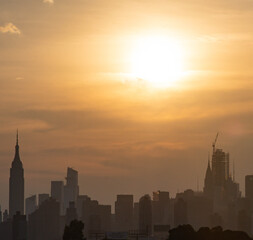 Fototapeta na wymiar sunset over the city silhouette skyline with vivid sun and sky 