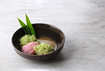 Putu Mayang or Petulo, Indonesian Traditional Javanese Snack Made of Rice Flour Strands Curled up into a Ball with Food Coloring, Served with Coconut Milk and Palm Sugar Syrup. White Background