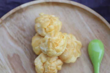 Choux cream, small fluffy creamy yummy vanilla inserted in round dessert as cold fresh sweet on wood plate.