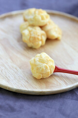 Choux cream, small fluffy creamy yummy vanilla inserted in round dessert as cold fresh sweet on wood plate.