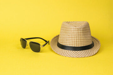 Men's summer hat and sunglasses on a yellow background.