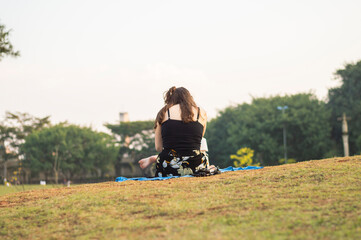 Young girl seated and reading a book in a park