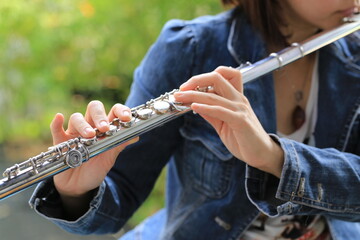 Flute classical instrument player playing song. Instructor practicing bronze woodwind for orchestra as solo with green bokeh outside with nature. - obrazy, fototapety, plakaty