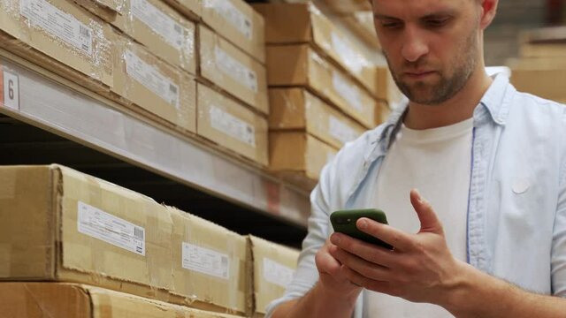 Man scans boxes of goods in a warehouse with a smartphone.