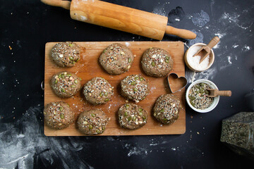 Brown whole wheat bread with multi grain in preparing to get dough for baknig as healthy bread on black background with wood board and roll. Sesame and seeds on bread.