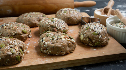 Brown whole wheat bread with multi grain in preparing to get dough for baknig as healthy bread on black background with wood board and roll. Sesame and seeds on bread.