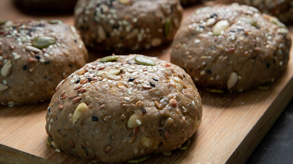 Brown whole wheat bread with multi grain in preparing to get dough for baknig as healthy bread on black background with wood board and roll. Sesame and seeds on bread.