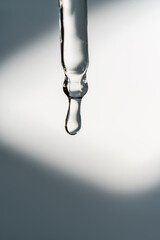 A drop of cosmetic oil falls from the pipette