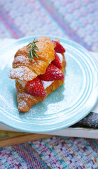 Croissant with strawberry and white softly mousse cream on blue ceramic plate with icing. French dessert assorted red berry.