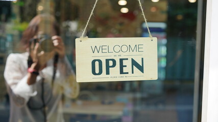 Open and closed flip sign in front of coffee shop and restaurant glass door. Wooden sign with...