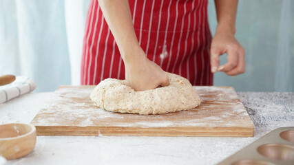 Whole wheat bread from homemade whole grain dough made by woman with red apron. Healthy pastry with many grains.