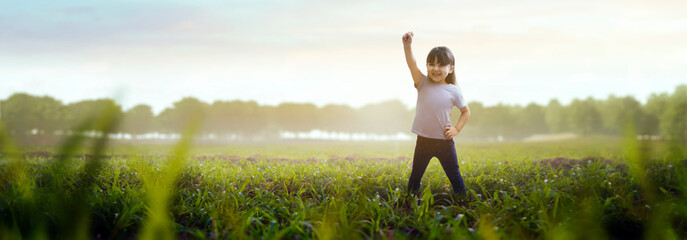happy girl playing in a green field with a fist in the air