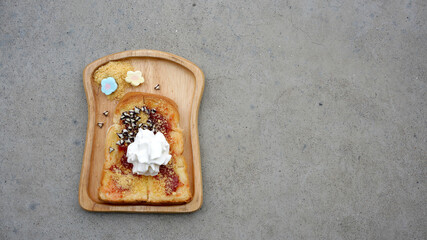 bread with strawberry topping and whipping cream serving with marshmallow on wooden plate