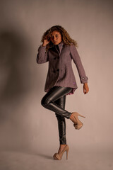 vertical portrait of a curly model wearing a jacket, black pants and heels