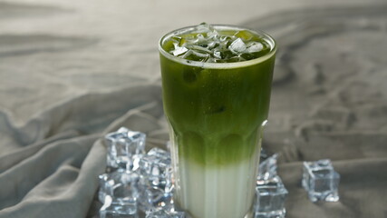 Green tea latte Japanese beverage into iced milky in tall glass on black background. Cold refreshment healthy menu. Matcha latte on ice.