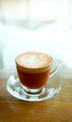 Thai tea latte art in short transparent cup in coffee shop. Light brown sweet tea with milk serving in hot.