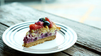 Fruity homemade cake with strawberry, cherry and cheese. Cheesy tart with crispy cracker on plate in bakery shop.