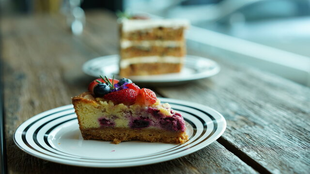 Fruit berry carrot cake on plate, settle on wooden table near window light. Dessert or sweet with nice setting