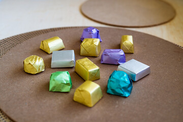 wrapped luxury chocolates in various colours for different flavours on a brown background.