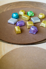wrapped luxury chocolates in various colours for different flavours on a brown background.